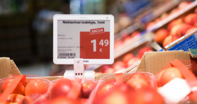 A price tag displaying a special offer for nectarines in a store. The price is shown as 1.49 euros per unit, with the word 'AKCIJA' (meaning 'special offer' in Lithuanian) highlighted in red. Nectarines are visible in red netted bags surrounding the price tag.